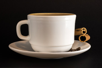 White cup of hot coffee and Cinnamon sticks isolated on black background.