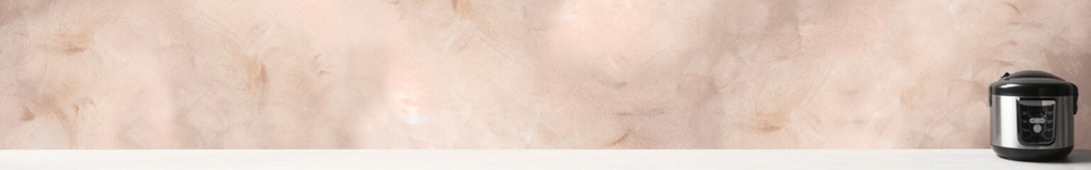 Modern electric multi cooker on table against color background. Space for text