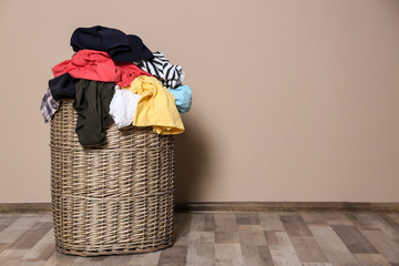 Laundry basket with dirty clothes on floor indoors. Space for text