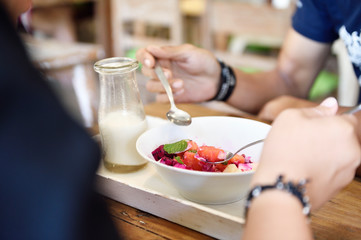 Couple sharing a healthy breakfast bowl of tropical fruit, granola and coconut smoothie