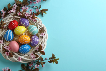 Flat lay composition with painted Easter eggs and blossoming branches on color background, space...