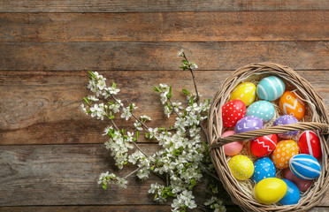 Flat lay composition with painted Easter eggs and blossoming branches on wooden background