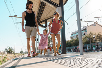Modern parents with girl on railway station