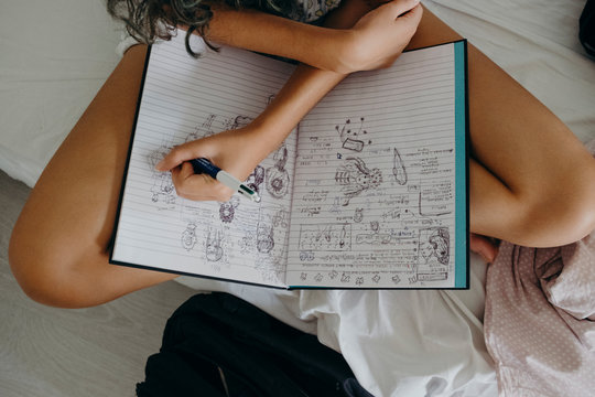 Anonymous young female model woke up and drawing in her sketch book in bed