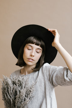 woman in hat posing for portrait holding dried flowers