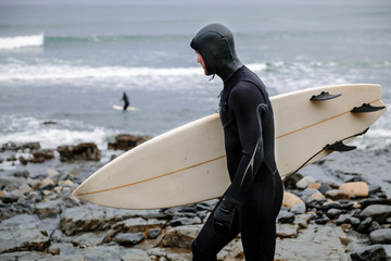 Surfer from the profile going down the hill towards the water.