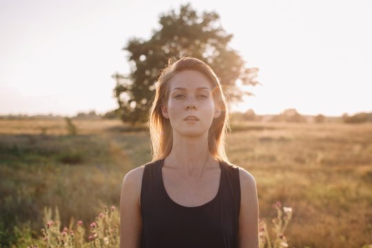 Portrait of young blond female in sunset light with rainbow sunbeam