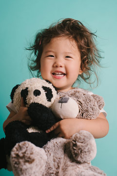 Little kid hugging stuffed animals