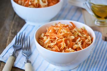 Salad with fresh cabbage, carrots and olive oil in a white bowl