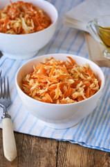 Salad with fresh cabbage, carrots and olive oil in a white bowl