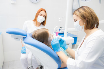 a female dentist and her assistant treat a little girl's teeth