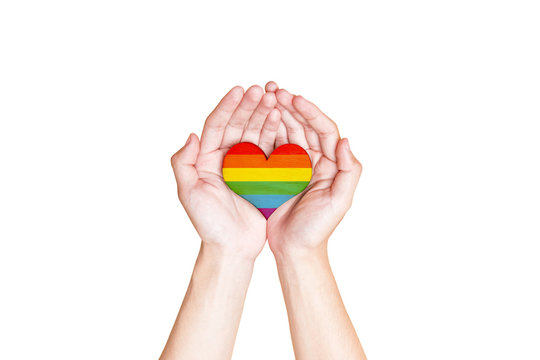 Human hands holding heart with rainbow flag as a symbol of LGBT