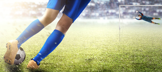 Football player man kicking the ball in the penalty box and asian goalkeeper trying to catch the ball