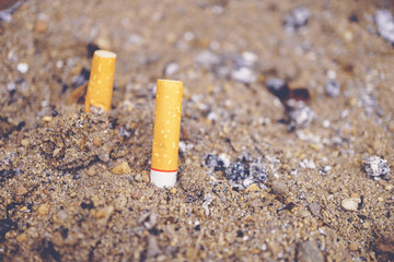 Cigarette in an ashtray, Cigarette stub in ashtray, Close-up discarded Cigarette in outdoors ashtray.