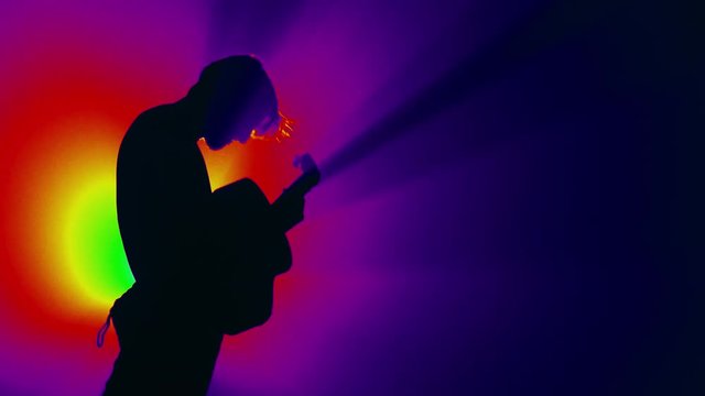 Concert rock band performing on stage with singer guitar. Stage light, smoke. One man.