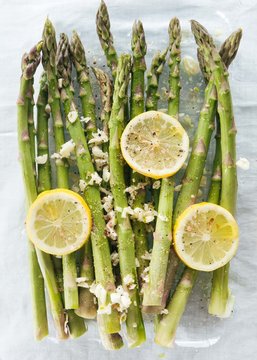 Pre-roasted asparagus, lemon, garlic on glass plate with linen tablecloth