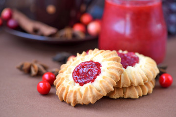 Shortbread cookies with jam in the middle on plate against brown background
