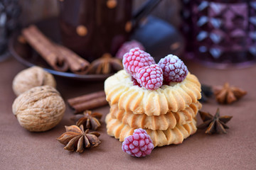 Shortbread cookies with frozen raspberries on brown background