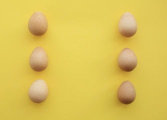 Five eggs of Guinea fowl symmetrically positioned by three on yellow background.