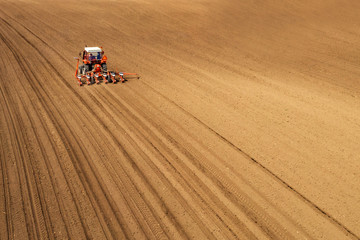 Aerial view of tractor sowing and planting corn in field