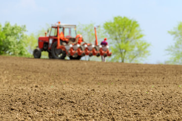 Farmer repairing tractor with seeder in field