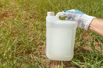 Farmer holding insecticide jug in wheatgrass field