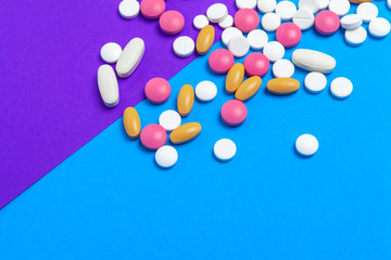 A pile of multicolored pills on blue background. Top view.