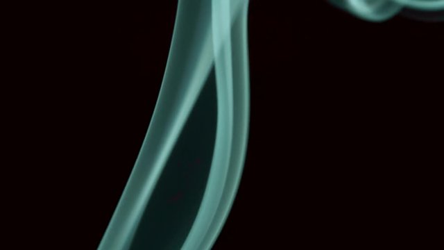 Thin trickle of white smoke slowly rising graceful twists up on black background. White smoke blowing from bottom to top. Closeup