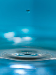 water splash in colorful background with a drop of water flying from above