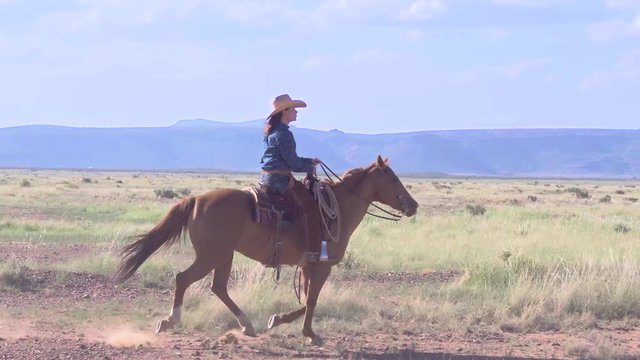 Confident Female Rancher Crosses Western Landscape By Horseback