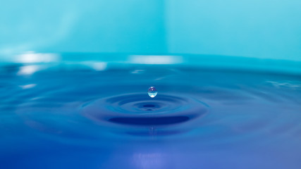 water splash in colorful background with a drop of water flying from above