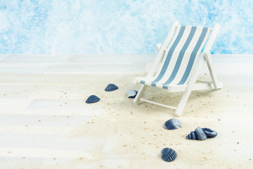 Maritime background with sand, shells and a blue and white striped beach chair