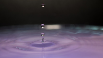 water splash in colorful background with a drop of water flying from above