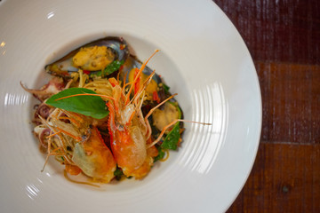 Spicy Seafood Spaghetti stir fried (Pad Cha) rolled in the fork on white dish of luxury restaurant