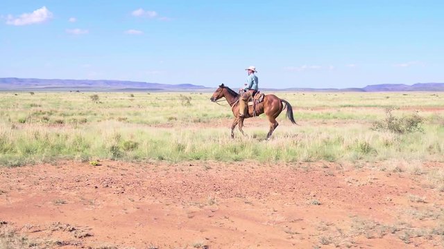 Rancher on horseback, galloping through Western landscape of Texas