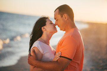 Young couple of lovers man and woman hug kiss and laughing on the seashore on sunset. Love near sea. Emotions Summer Lifestyle People Feelings Travel Anniversary