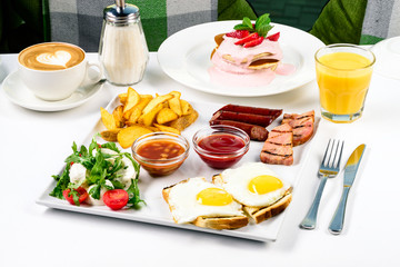 Huge healthy breakfast spread on a table with coffee, orange juice, fruit, muesli, smoked salmon, egg