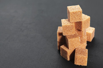 Natural brown sugar cubes on rough black background