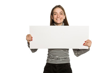 Young model in blouse shows an empty advertising board on white background