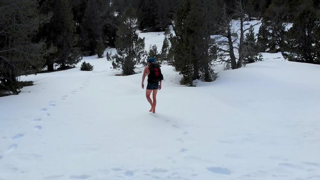 Man walks barefoot, with just shorts and backpack into frozen forest, Wim Hoff method cold conditioning practice