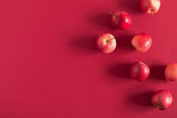 Red apples on a red background. Flat lay, top view, copy space
