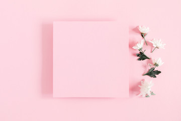 Beautiful flowers composition. White flowers and empty pink paper on pastel pink background. Valentines Day, Easter, Happy Women's Day, Mother's day. Flat lay, top view, copy space