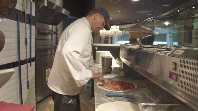 Pizzaiolo makes pizza In Italian Restaurant