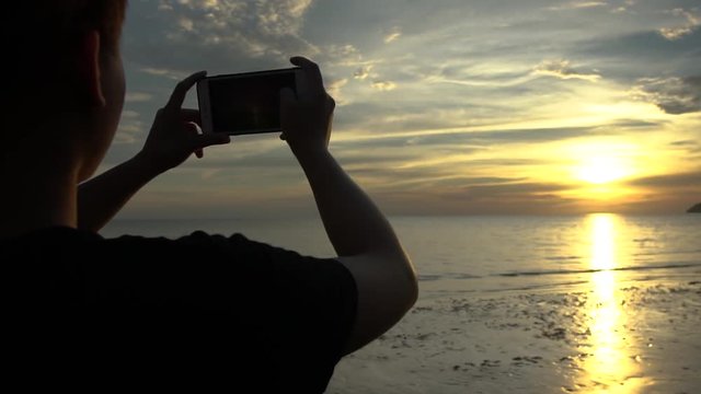 Girl taking sunset photo on the beach left side