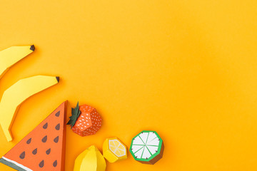 top view of various handmade colorful origami fruits isolated on orange with copy space