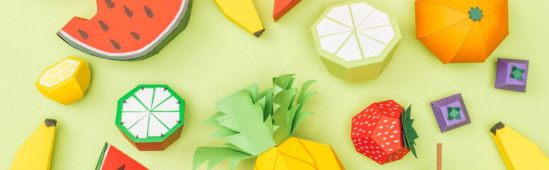 panoramic shot of colorful handmade paper fruits isolated on green