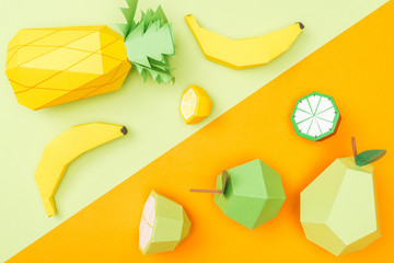 top view of handmade colorful origami fruits on orange and green
