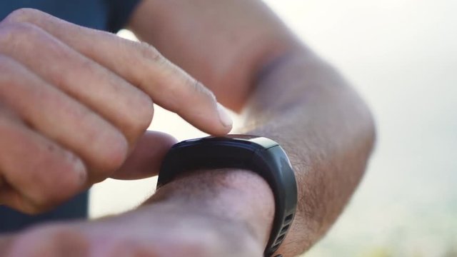 Young male runner adjusting smartwatch