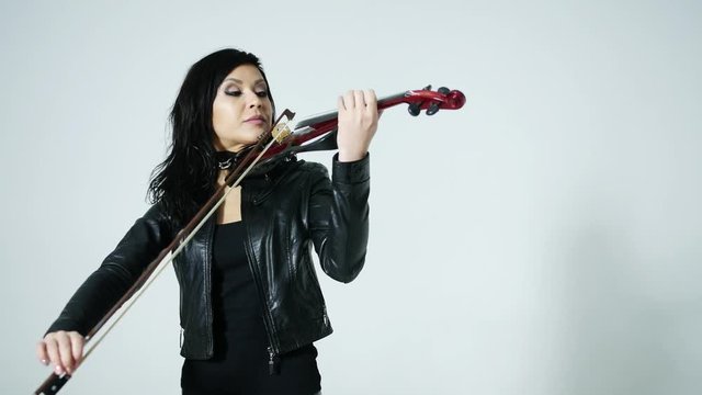slender sensual artistic young Asian girl in tight black leather clothes expressively plays the electric violin