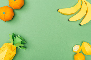 top view of handmade paper bananas, lemons, tangerines and pineapple isolated on green